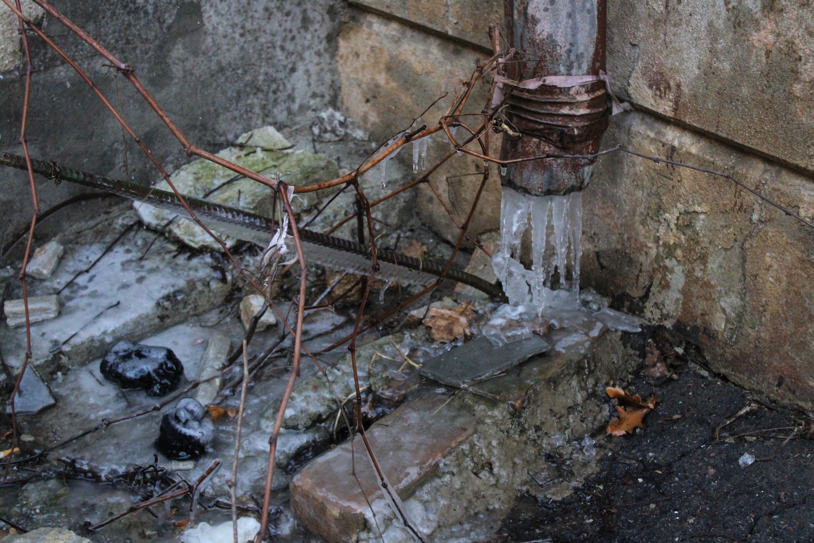 a fire hydrant next to a wall with ice on it